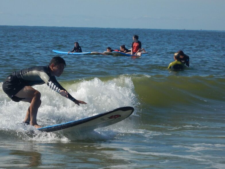 Surfers chillaxin' on the outside while a man escapes to the inside via board. | Photo by New York Surf School