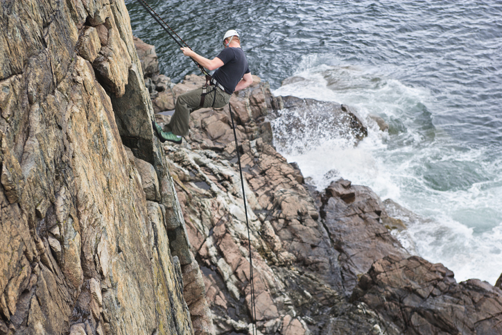 Man rappels down a cliff face.Man rappels down a cliff face on Otter Cliffs in Acadia National Park.