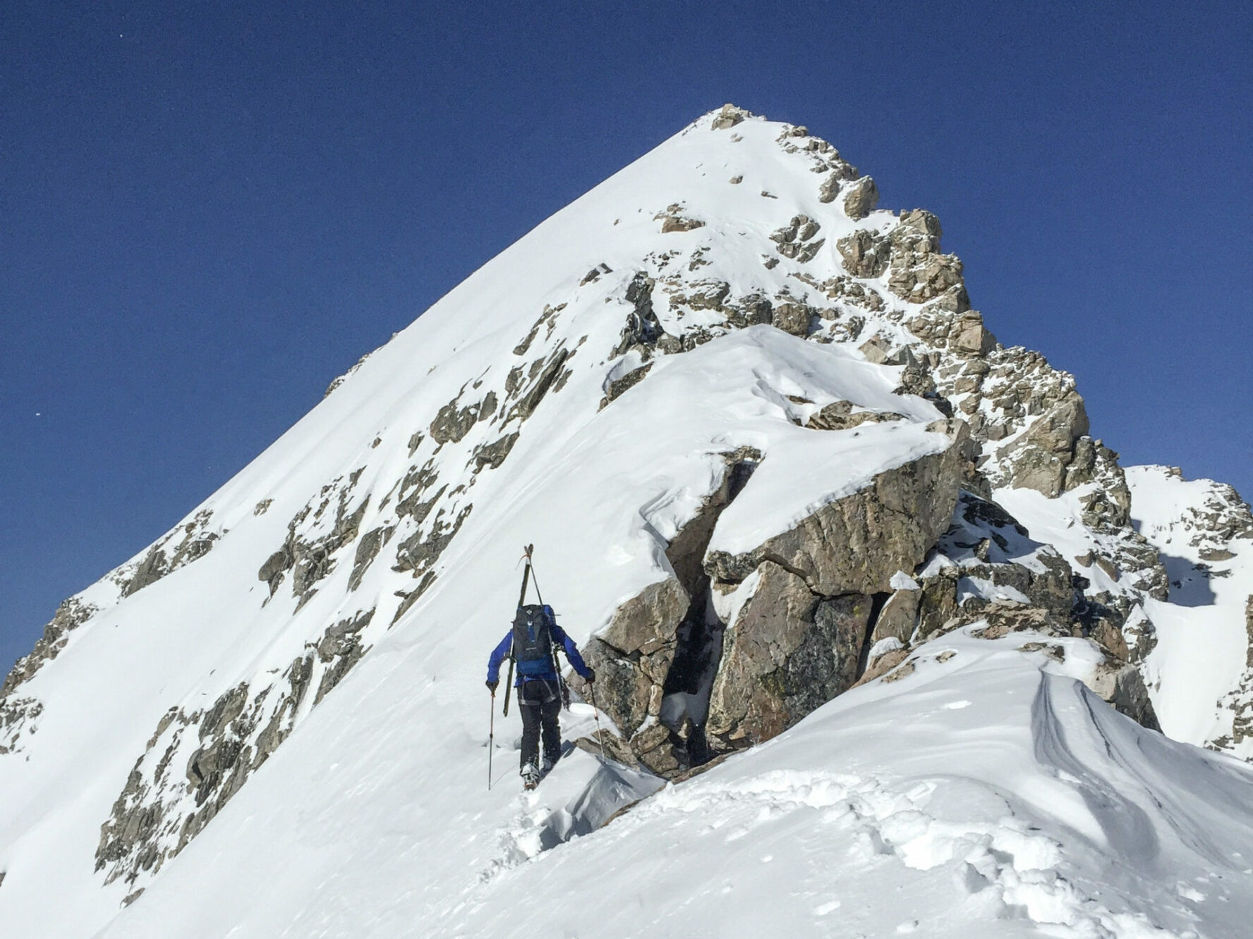 A ski mountaineer is close to the top of a peak in the Tetons.