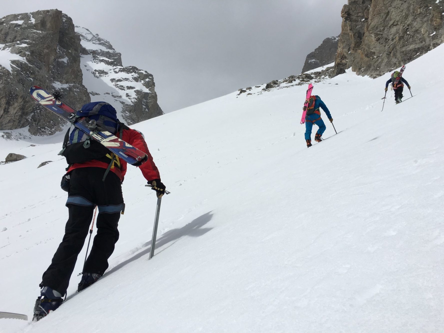 A group of ski mountaineers climbing to get to the top of a steep high-altitude ski line in the Tetons during a ski mountaineering camp.