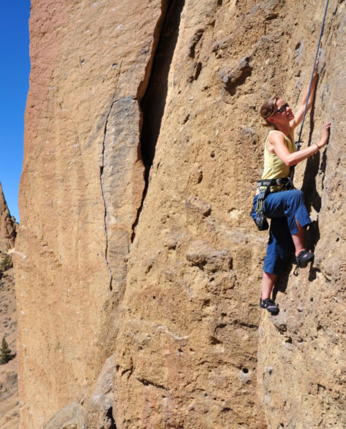 "A woman ascends a cliff at Smith Rock State Park, Oregon."