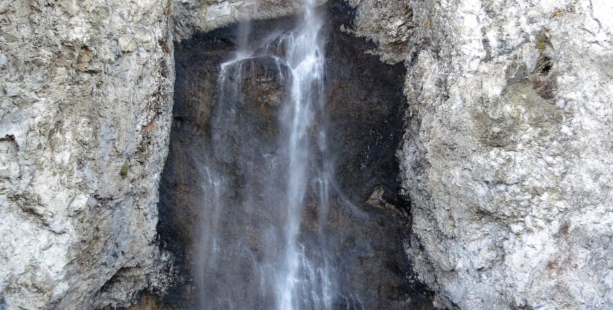 A hiker walking under the Fairy Falls in Yellowstone.