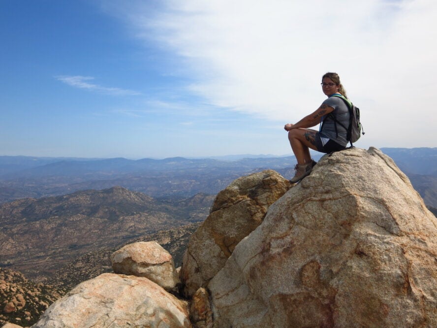 A hiker sits at the summit of El Cajon Mountain.