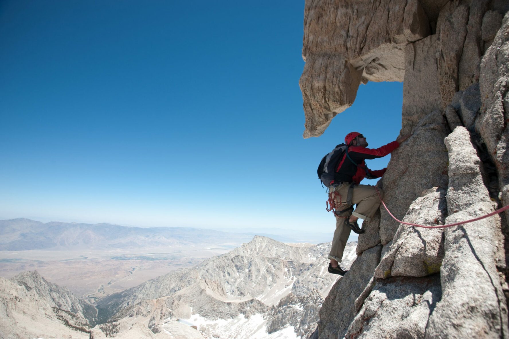 An alpine climber on a very exposed rock climbing route in High Sierra.