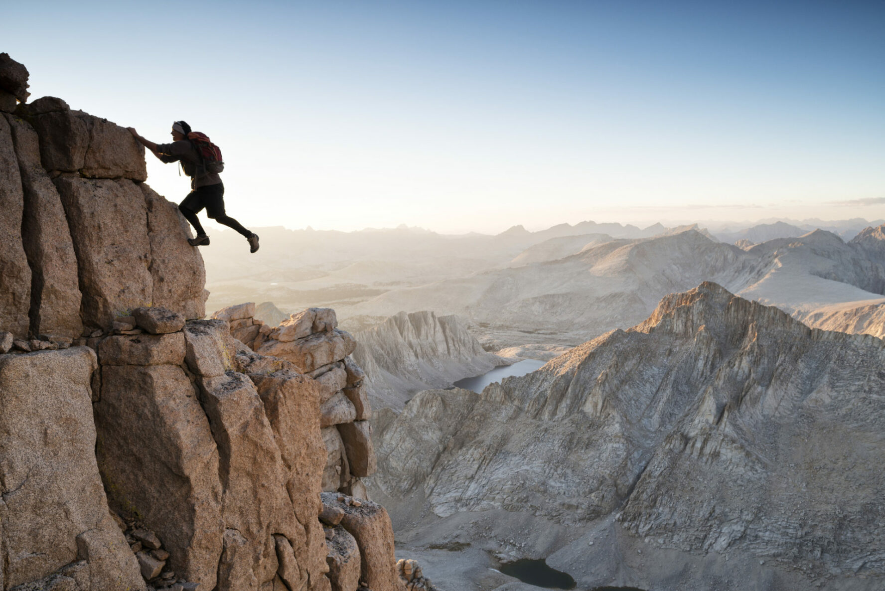 An alpine rock climber is nearing the summit in High Sierra on an exposed route.