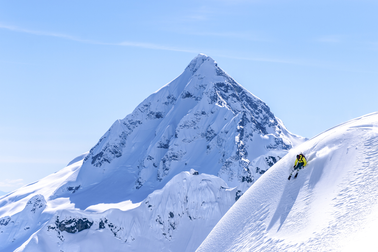 He sprays snow as he turns at speed, in the snowy Canadian Rockies
