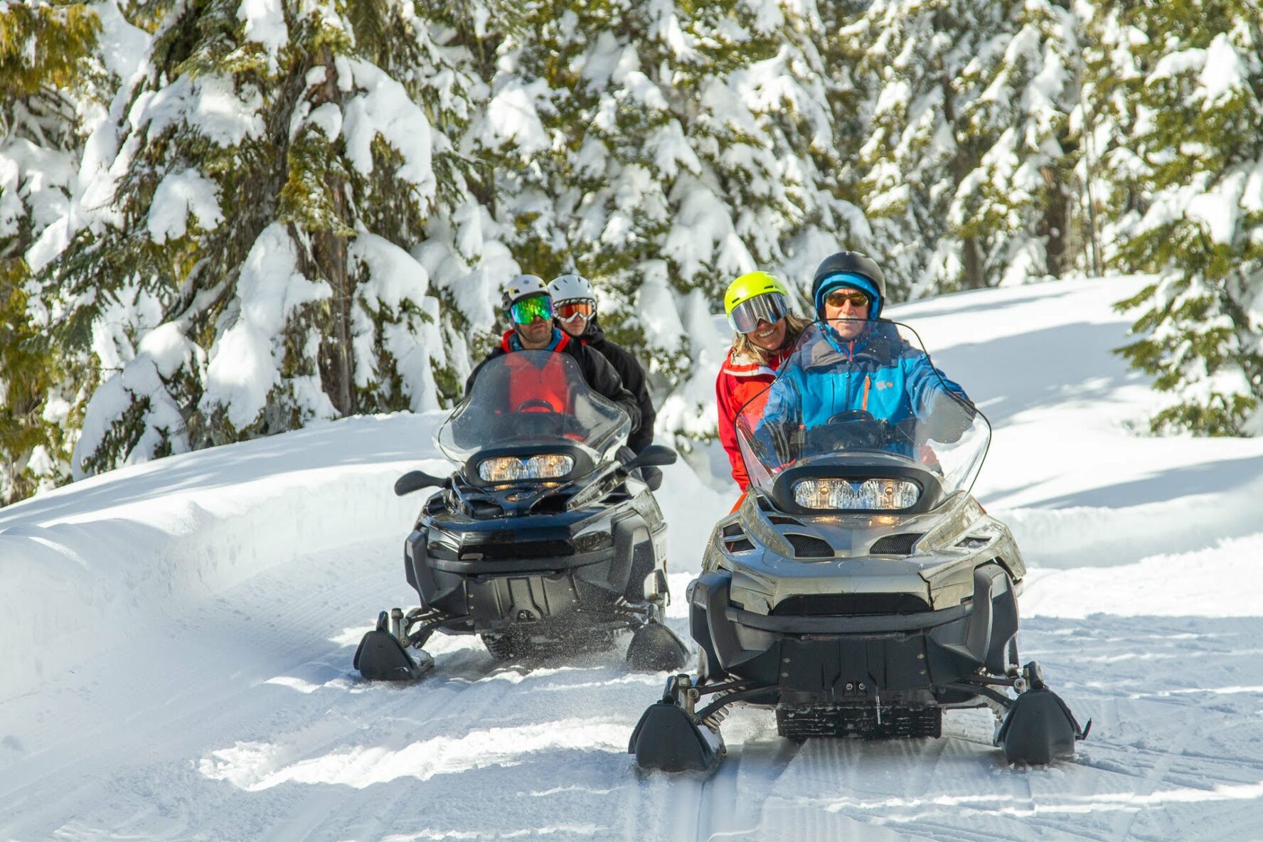 Skiers cruising on snowmobiles in British Columbia.