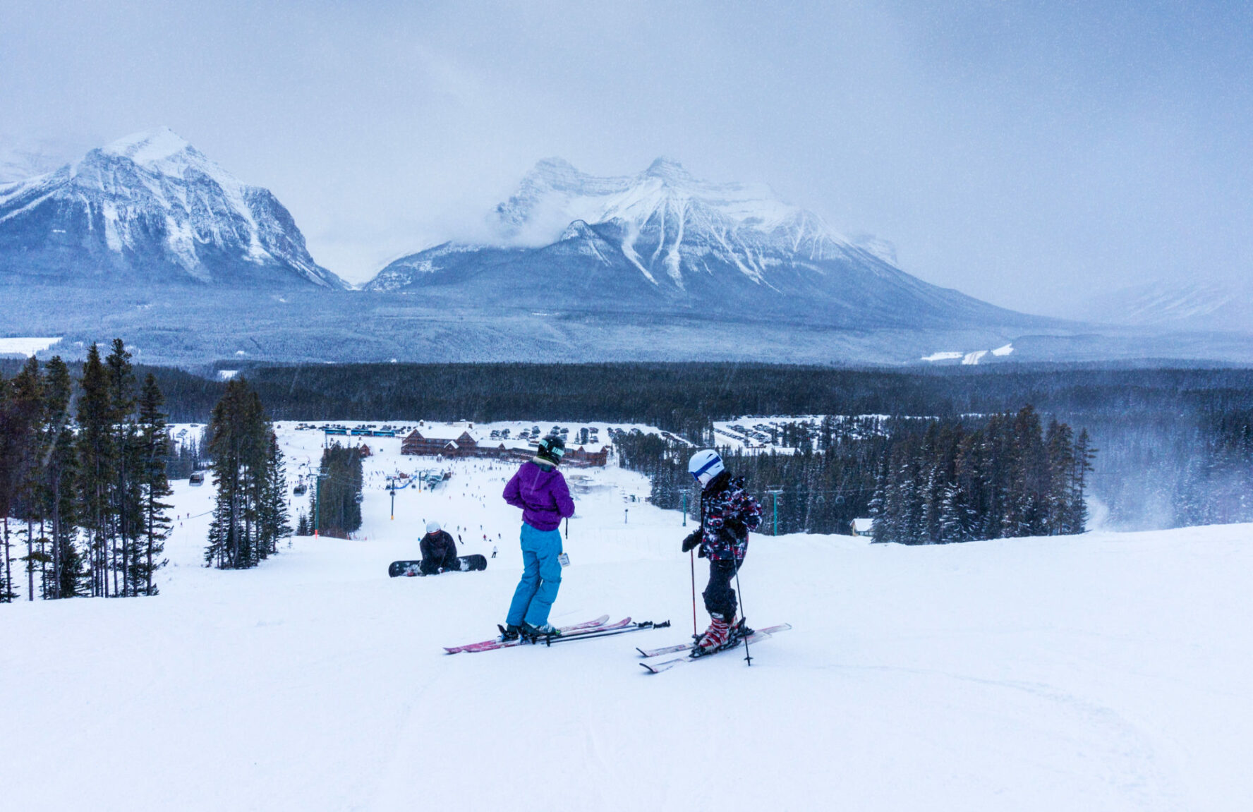 Backcountry skiers on a slope overlooking a lodge in Lake Louise