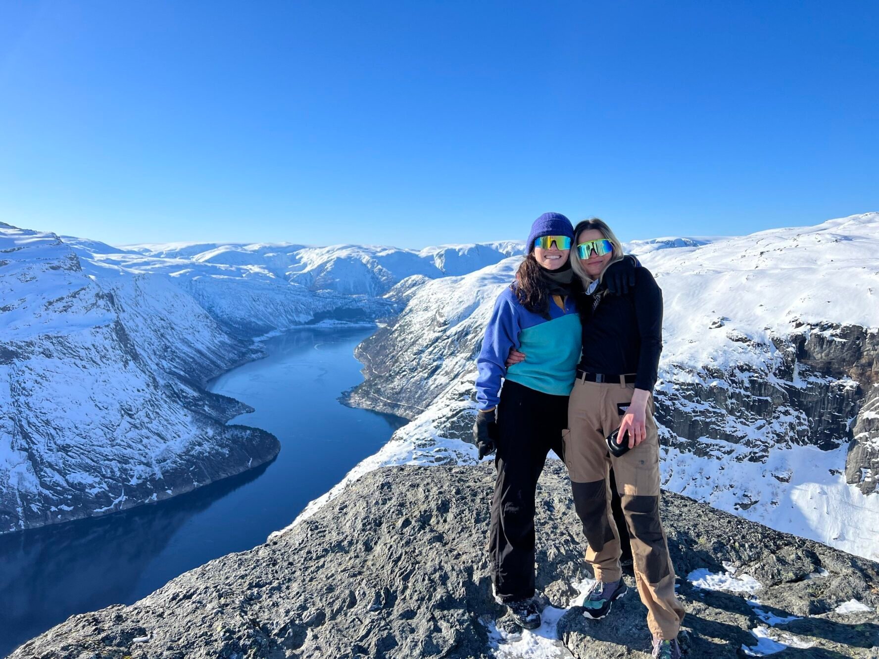 Two hikers smiling with a snowy landscape behind them on the Trolltunga winter hike