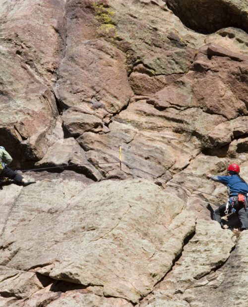 Pair of mountain climbers work together to scale a cliff high in the Colorado Rockies.