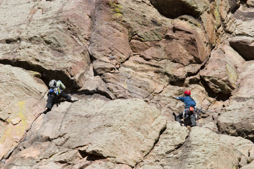 Pair of mountain climbers work together to scale a cliff high in the Colorado Rockies.