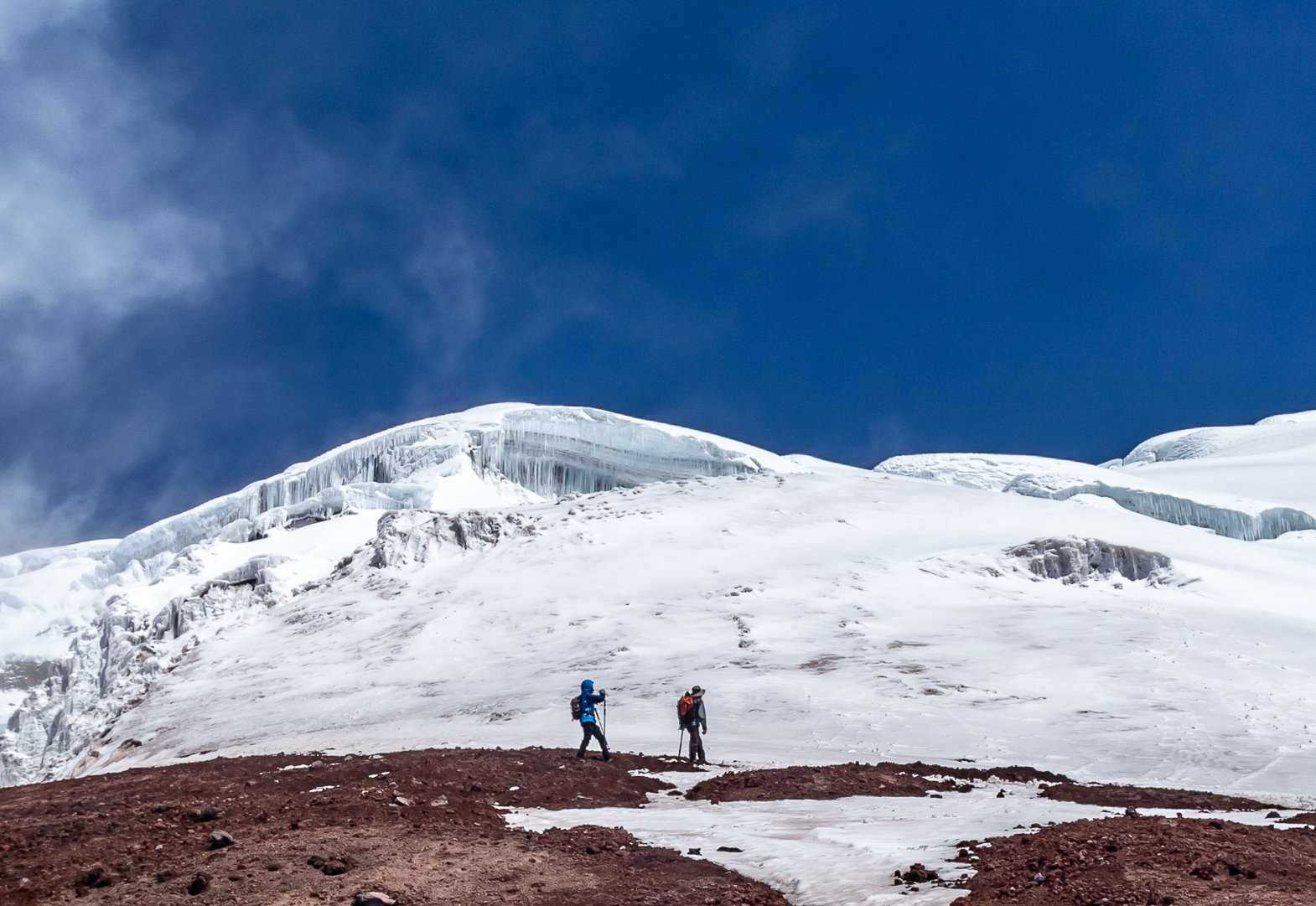 Two alpine climbers approaching the glacier at the top part of the Cotopaxi Volcano.