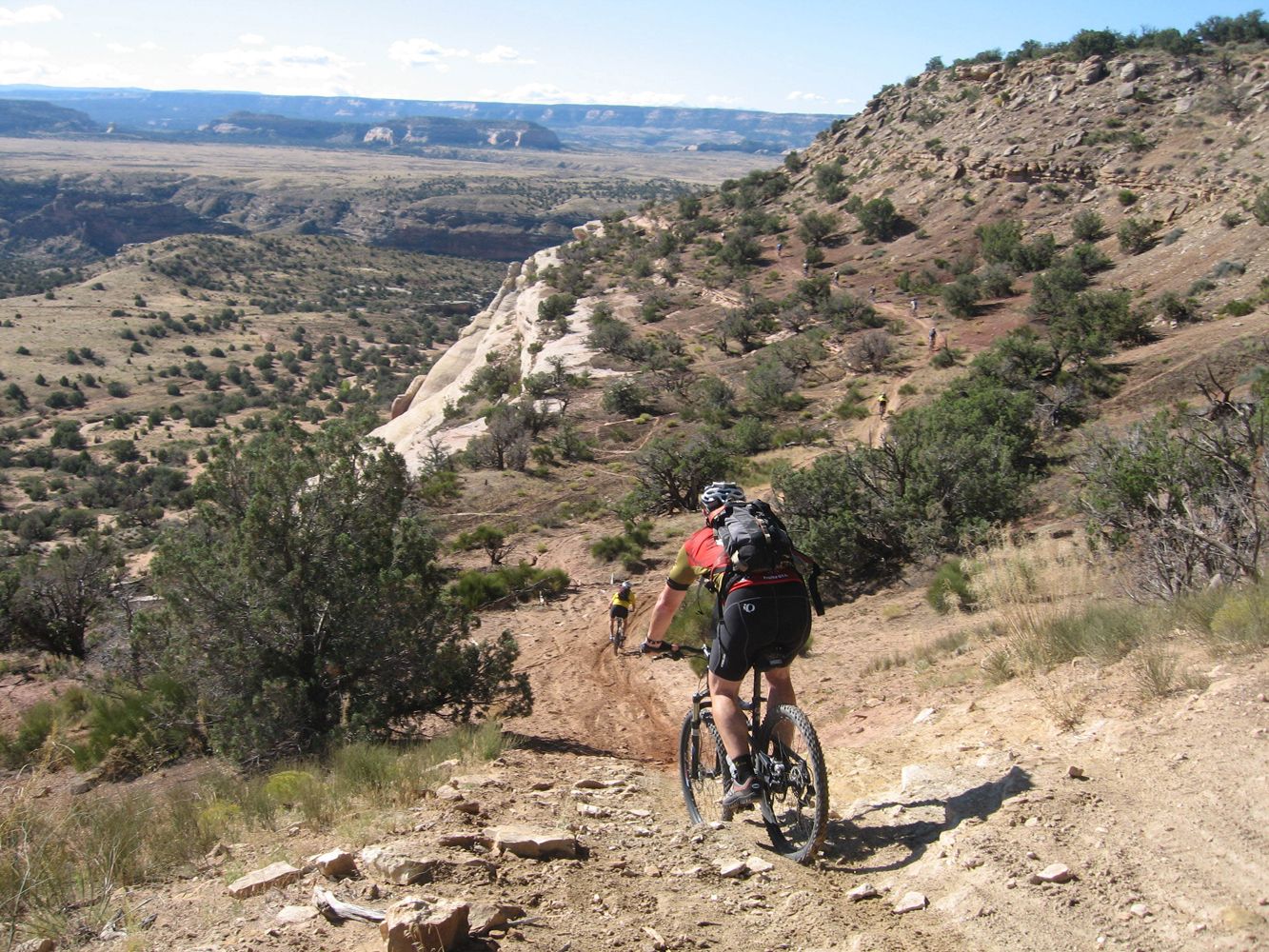 Mountain bikers riding downhill along the Kokopelli Trail, with typical desert landscapes of the American Southwest around them.