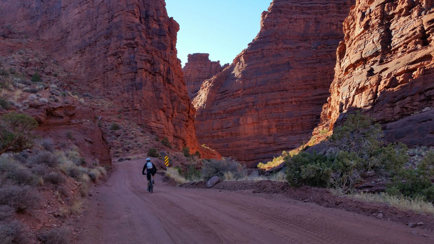 A mountain biker riding through a red rock canyon while on a Kokopelli Trail adventure.