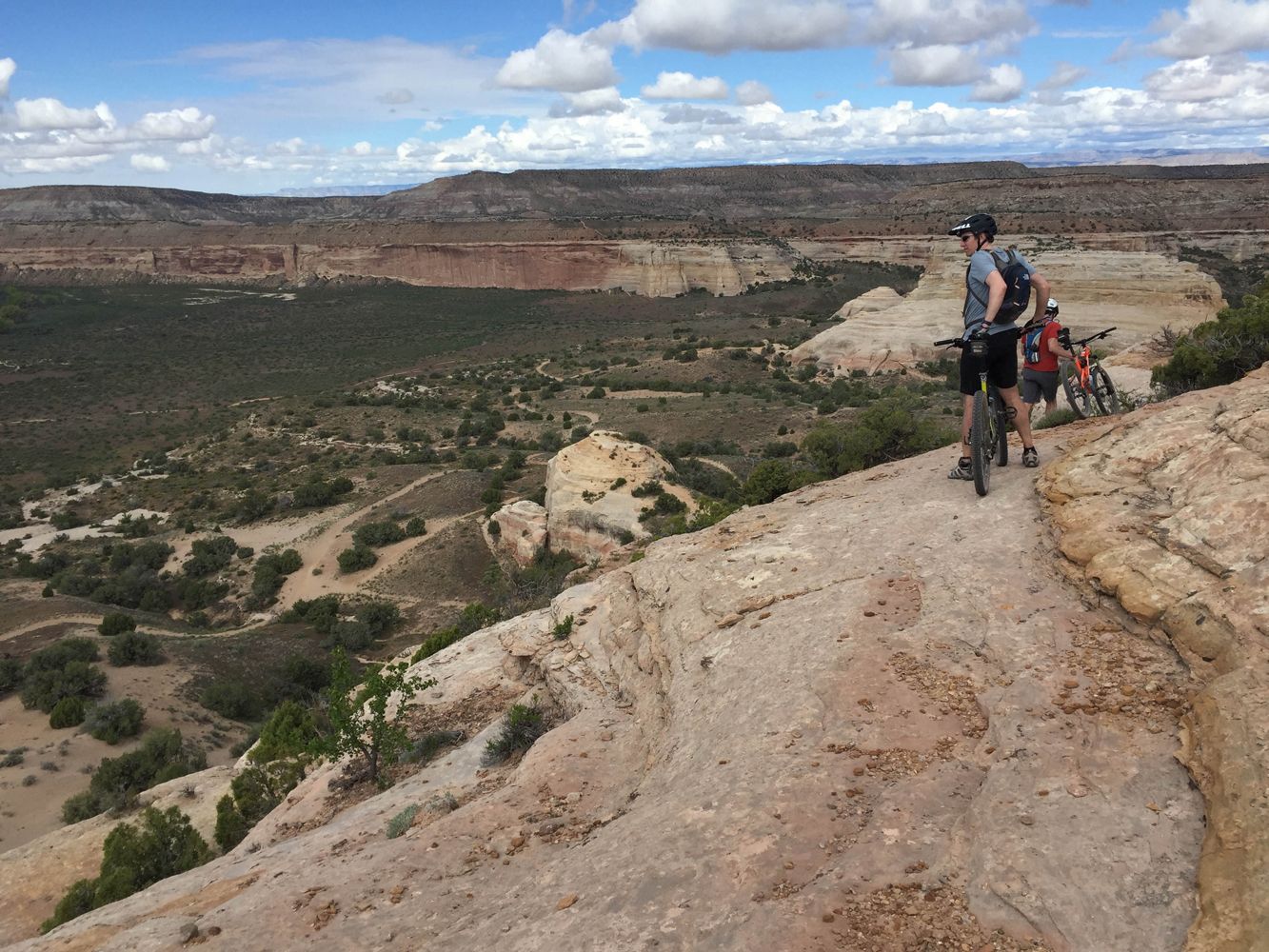 Mountain bikers taking in the views of a huge canyon seen during their Kokopelli Trail tour.