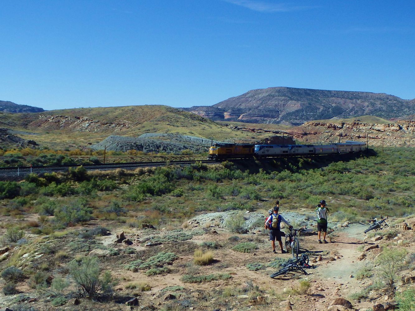 Mountain bikers taking a break from riding the Kokopelli Trail and looking at a train.