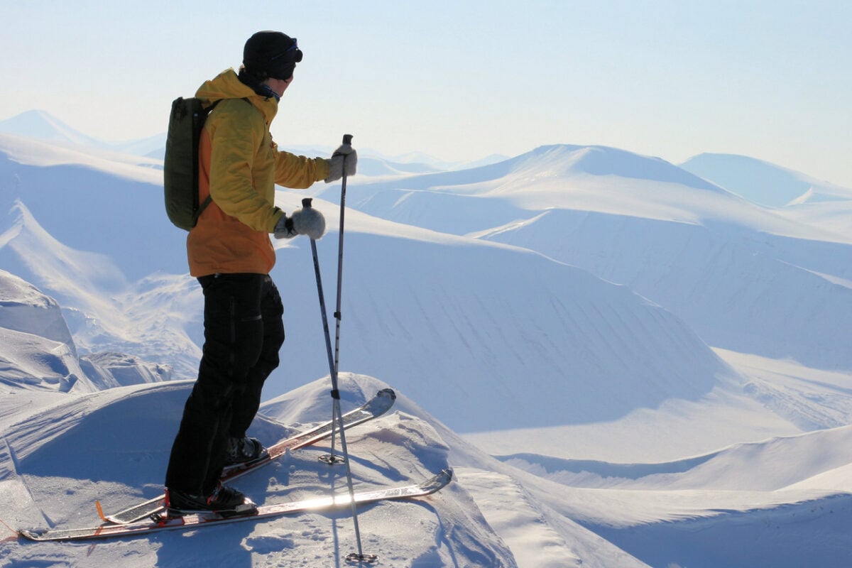 A skier enjoying the view over the snowy peaks and valleys in Svalbard