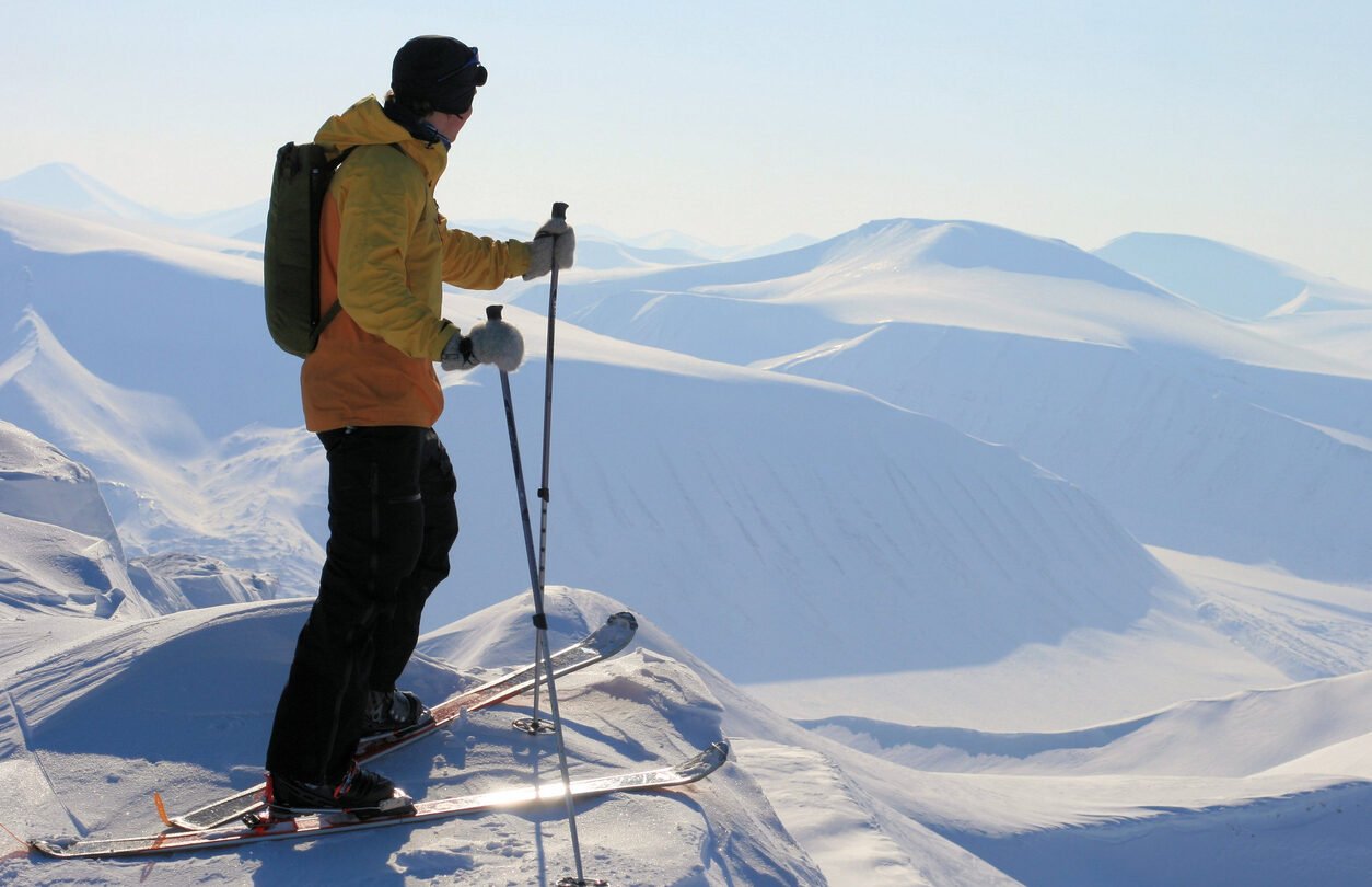 A skier enjoying the view over the snowy peaks and valleys in Svalbard