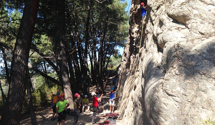 A group of people under a cliff on La Pedriza.