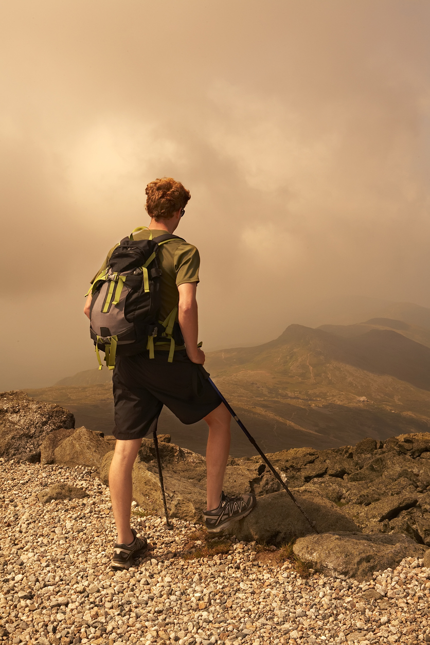 A hiker standing near the upper sections of Mount Washington looking down
