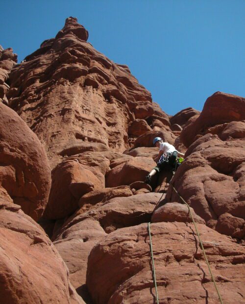 A climber ascending a tower in the Moab region