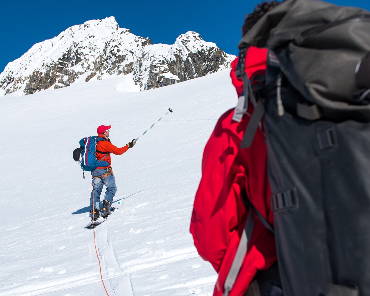 A ski tourer pointing at a slope in the Tantalus Range