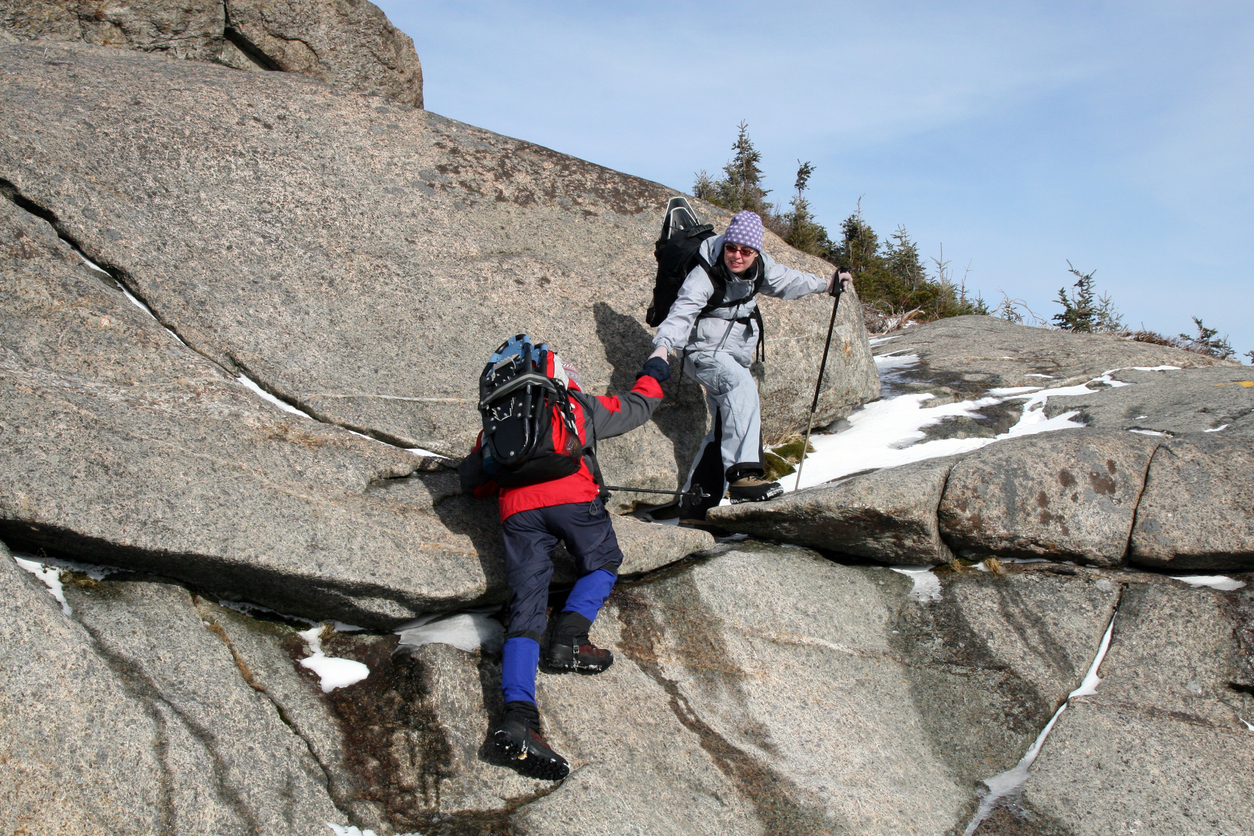 Hiker helping another one to climb.