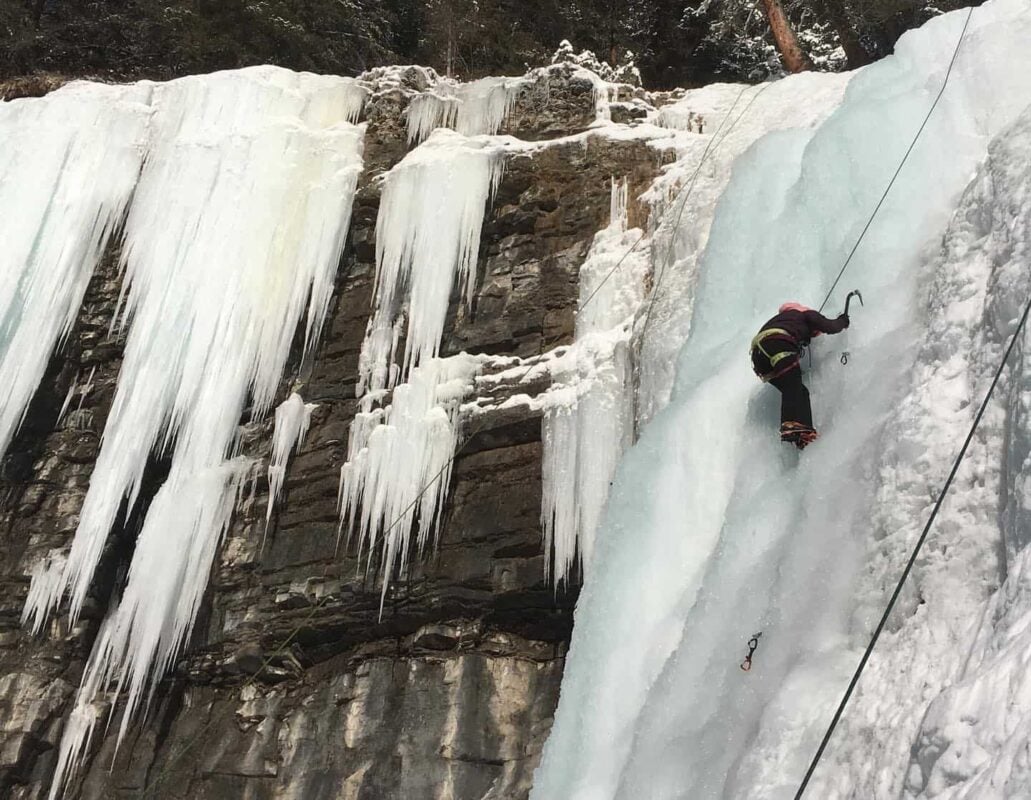 An ice climber on a frozen ice wall in the Canadian Rockies