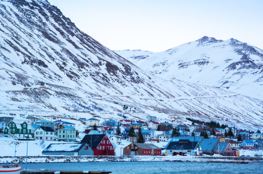  A cluster of houses in the coastal town of Siglufjörður sitting at the foot of a snowy mountain