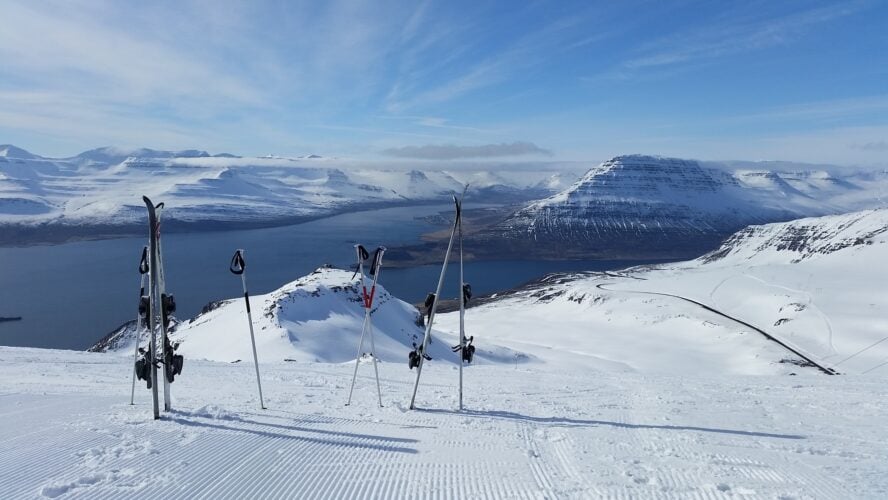 Two pairs of skis and poles stuck in the ground in a vast snowy landscape