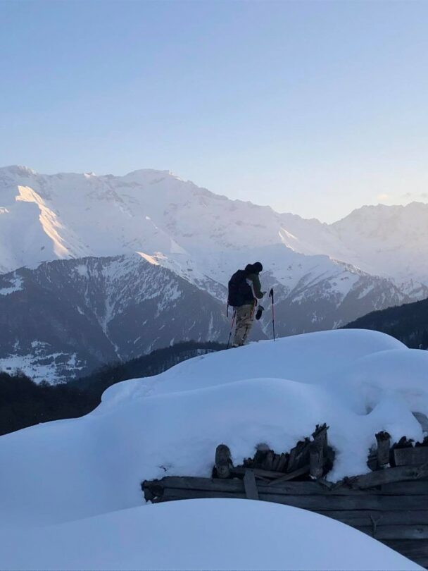 A lofty sniw-dusted mountain peak in the Georgian region of racha traversed by backcountry skiers