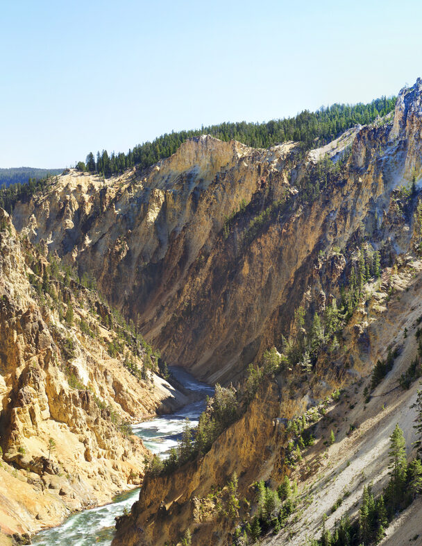 Couple relaxing and enjoying beautiful view of hot spring on vacation hiking trip. Beautiful Yellowstone Lake in the background and hot spring in foreground. Yellowstone National Park. Wyoming, USA