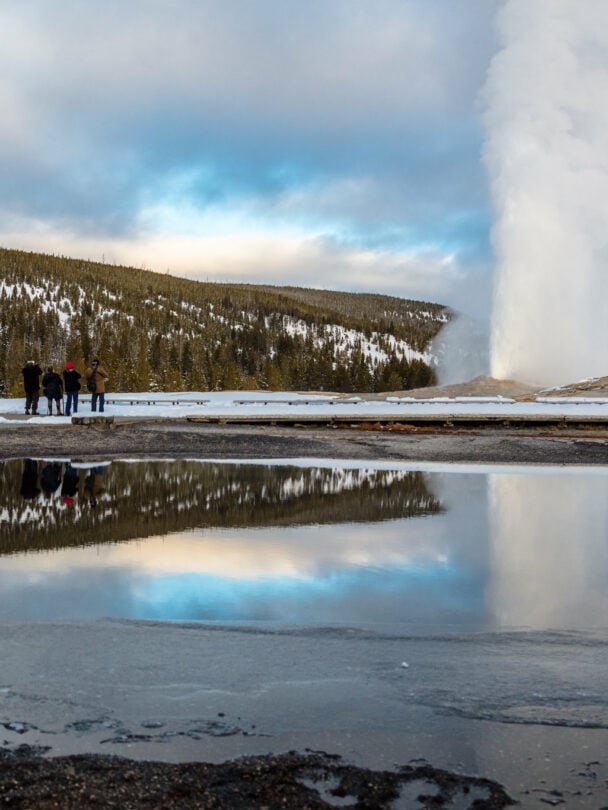 Couple relaxing and enjoying beautiful view of hot spring on vacation hiking trip. Beautiful Yellowstone Lake in the background and hot spring in foreground. Yellowstone National Park. Wyoming, USA
