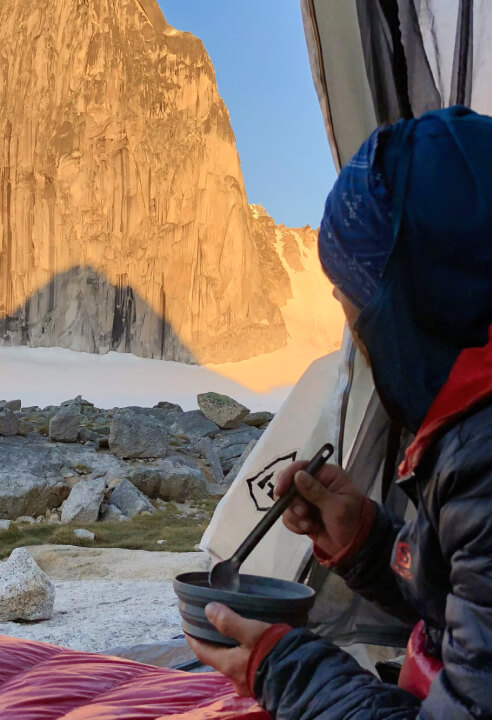 A backcountry skier having a warm meal while camping in mountains around Revelstoke.