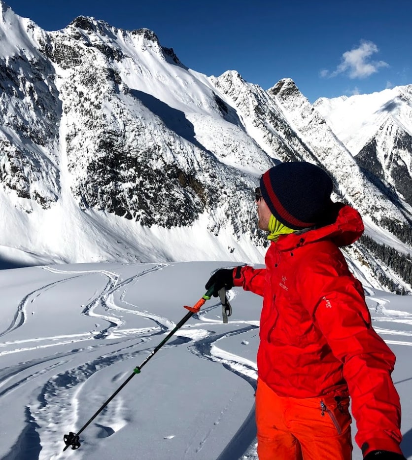 A skier in red admiring the mountains around Revelstoke