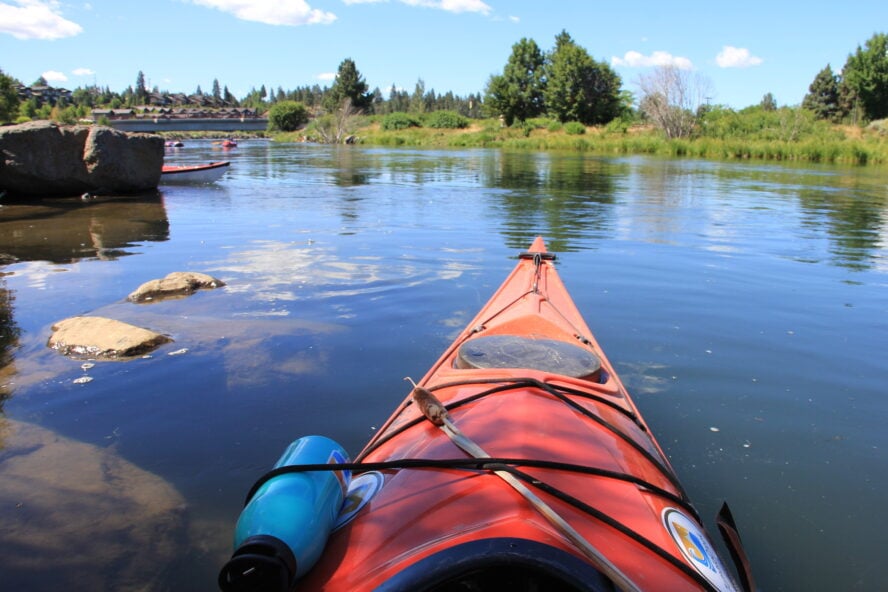 Kayaking photo looking out from the cockpit on the Deschutes River in the Old Mill District in Bend, Oregon. 