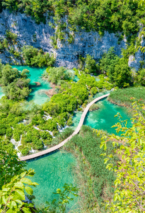 A designated trail in Plitvice Lakes, dividing a tuquoise lake in half.