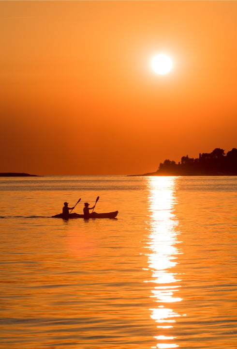 Kayaking on the Adriatic Sea among the orange sunset hues.