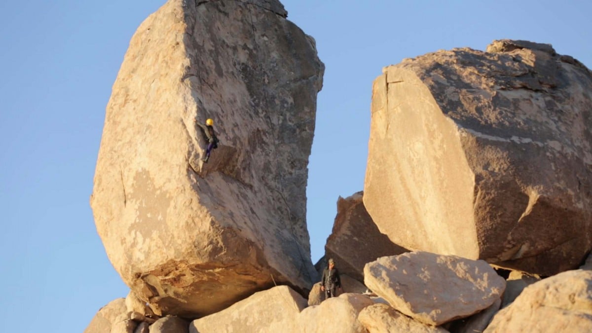 A climber ascending a rock formation in Joshua Tree National Park