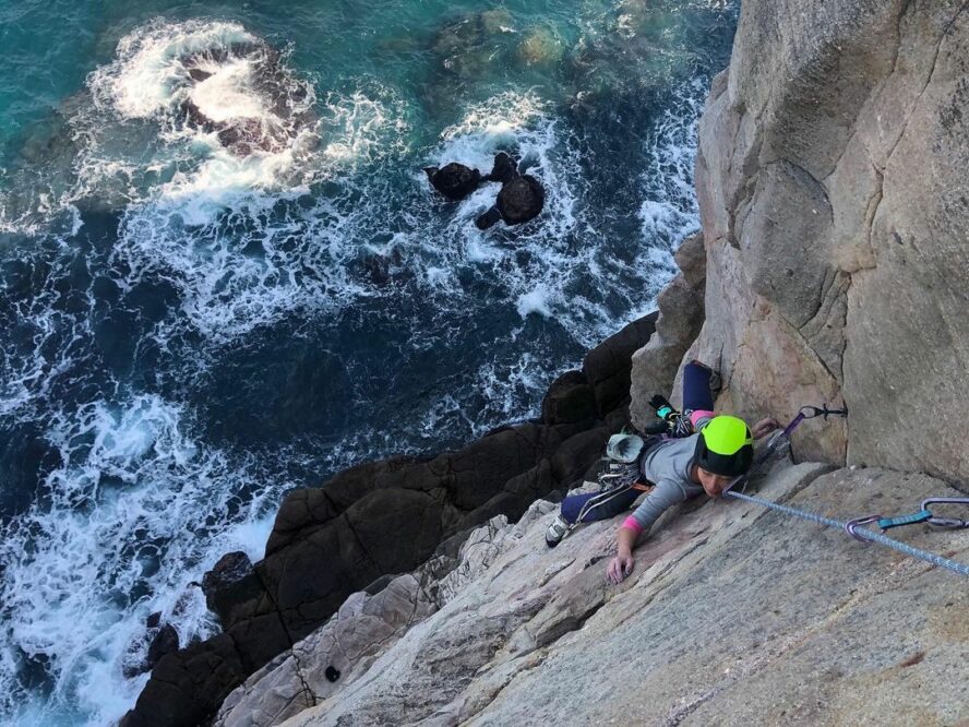 A female climber climbing at Long Dong, Taiwan, with the Pacific below