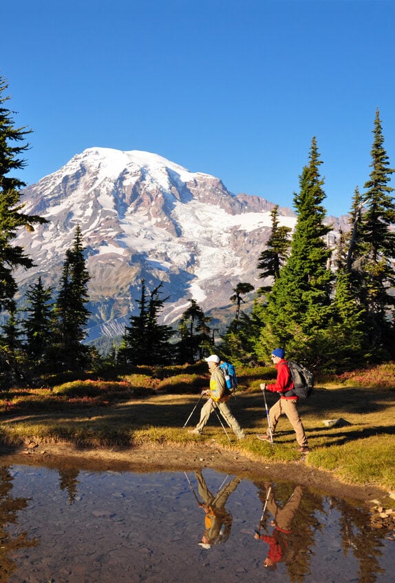 "Two hikers walk by a small pond in Mt. Rainier National Park, Washington State."