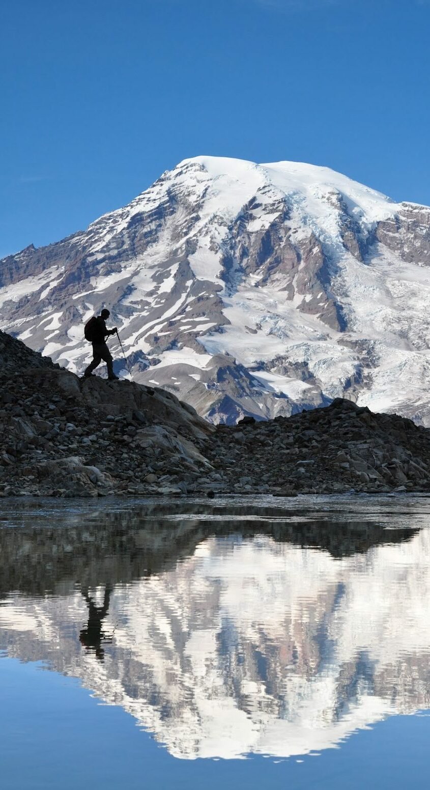 Peak in Mount Rainier and a hiker walking in front of it (C) DANNY WARREN