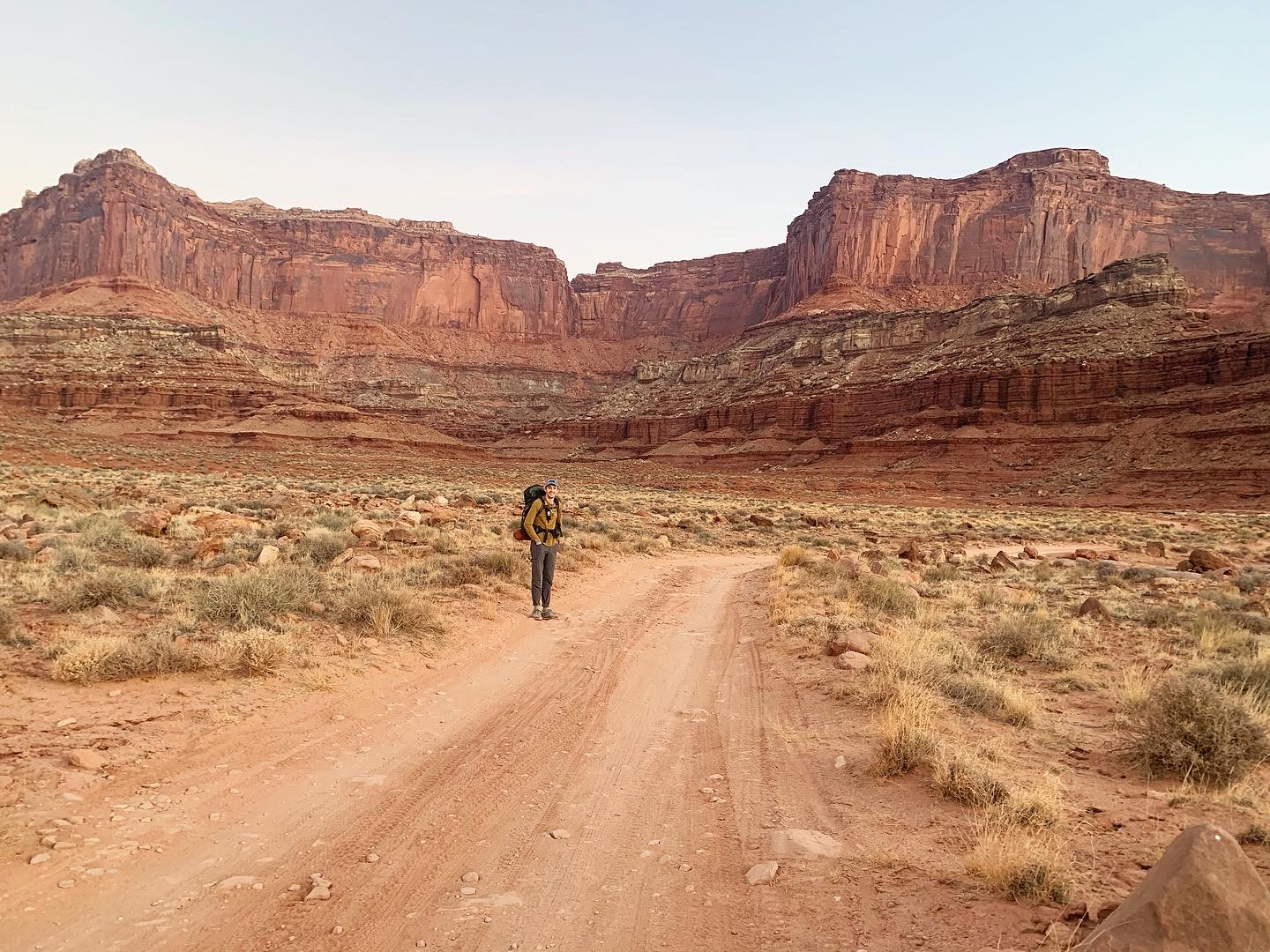 A hiker walking down a sandy path in Moab