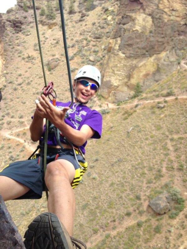 A young climber smiling and climbing in Smith Rock State Park