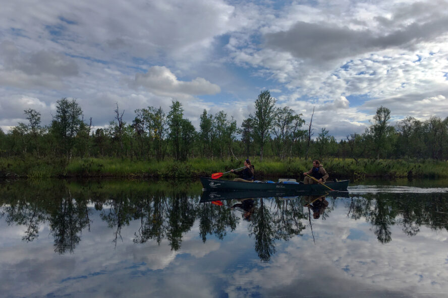 A couple kayaking on the Ivalojoki River, like a perfect mirror. 