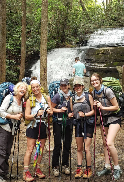 A group of hikers posing in front of the waterfalls in the Appalachian Trail.