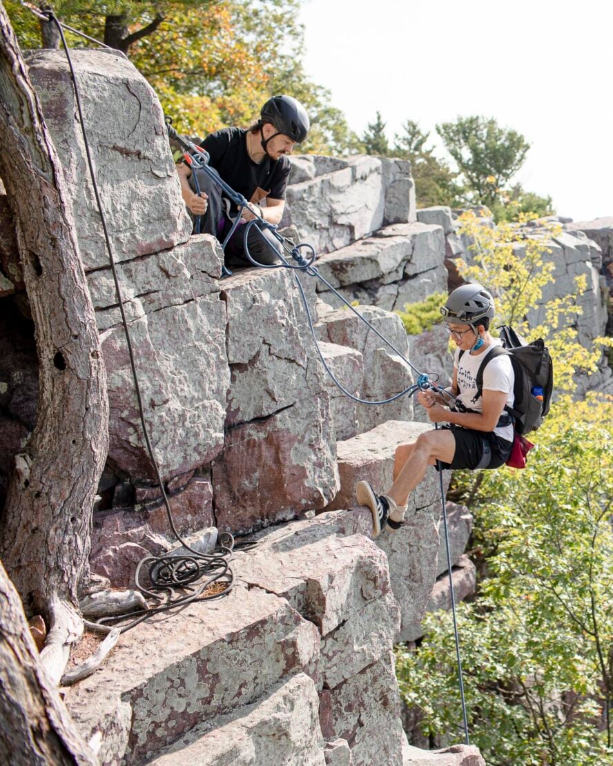 One climber secures from above as another climber rappels down a route in East Rampart. 