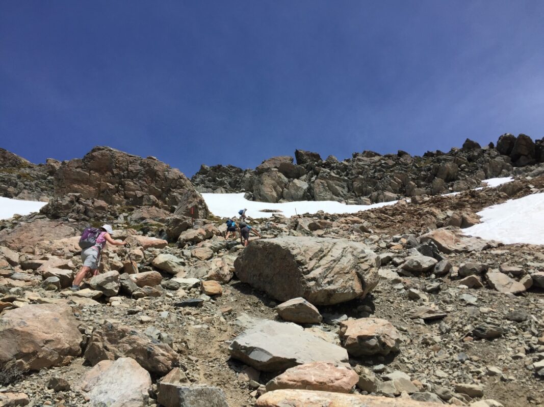 Hikers scrambling up Mueller Ridge, Sealy Tarns