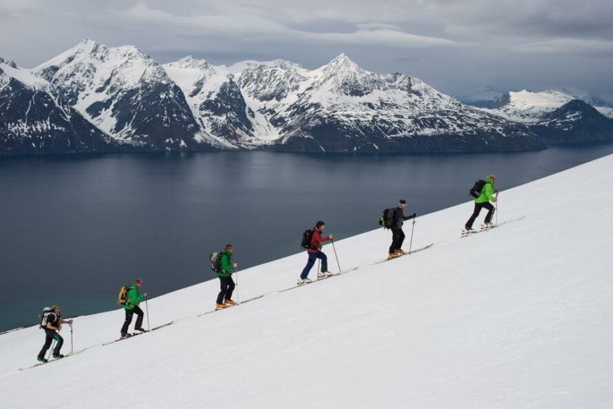 Skiers making their way up from the sea on a Lyngen Alps backcountry ski tour. 