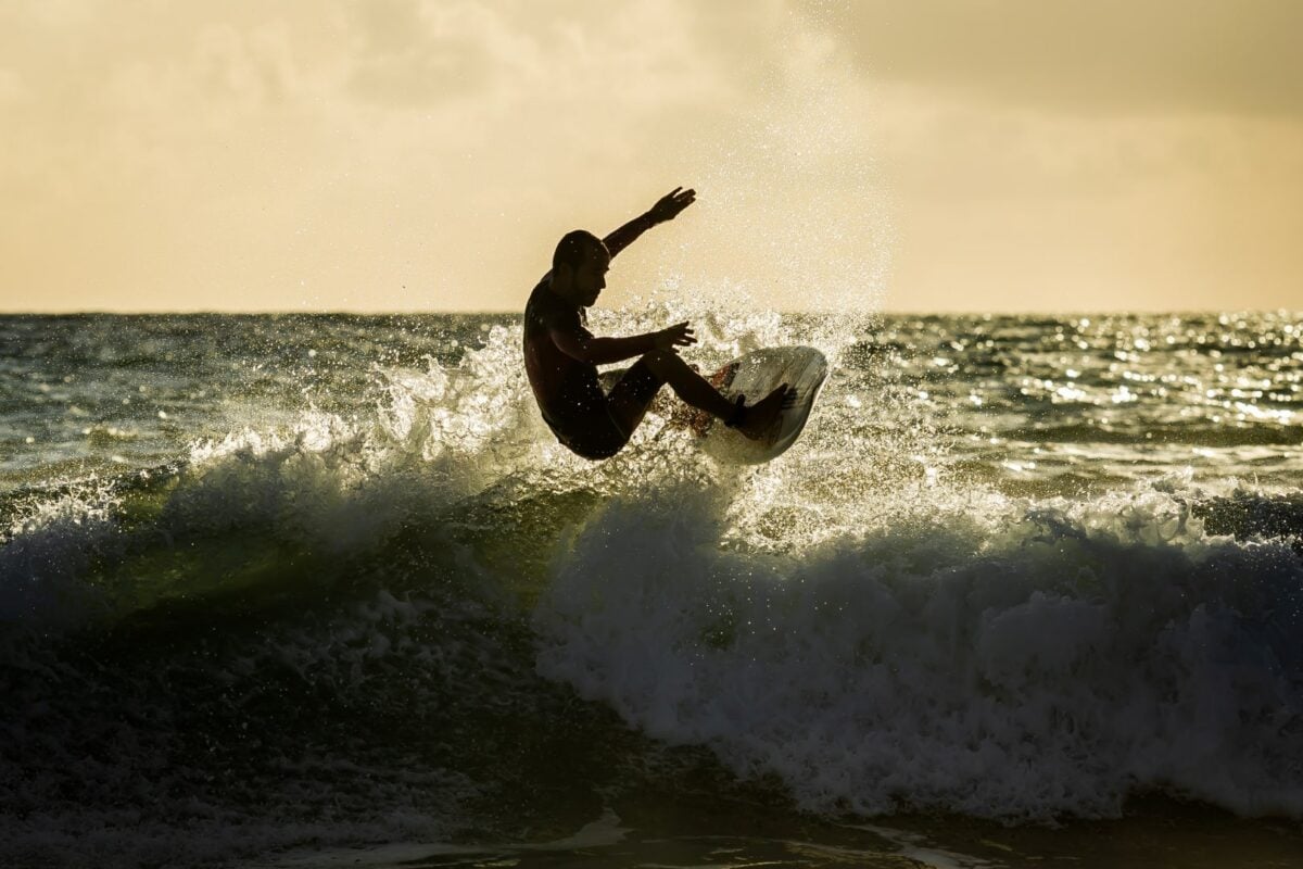 A surfer catching a wave at sunset in Norway